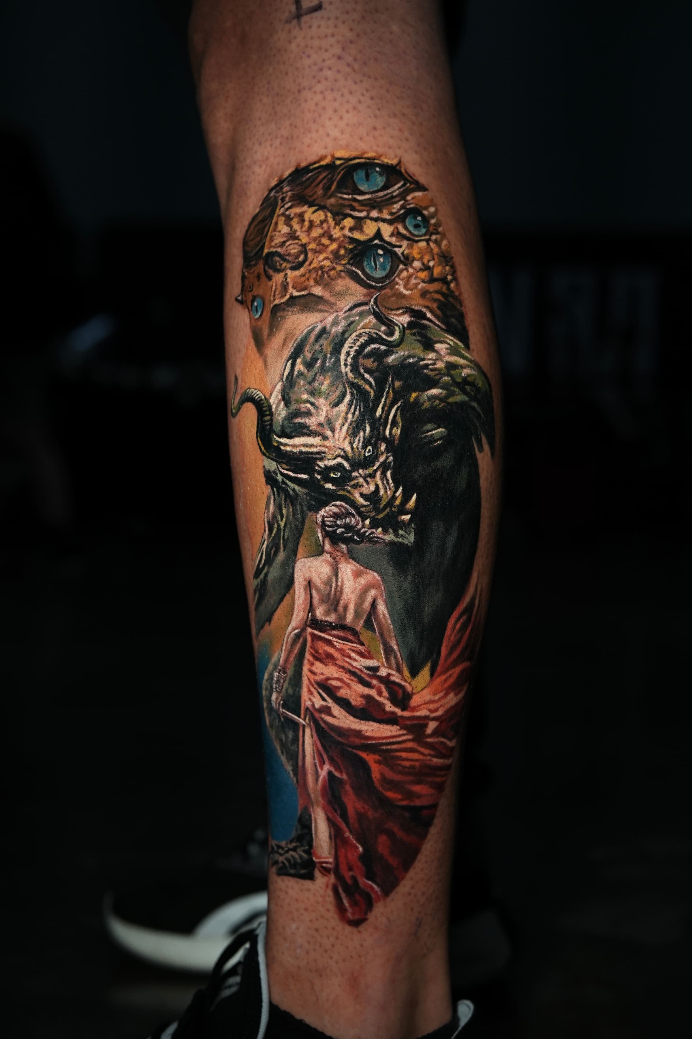 Color realism tattoo of a robed woman facing a horned demon, on the calf, by Rivas Indeed, San Juan, Puerto Rico